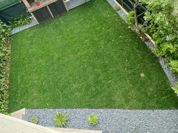 Césped natural bien mantenido con borduras y caminos de piedra