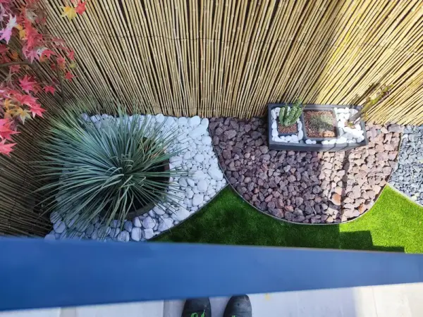Jardín con agaves, piedra decorativa y césped