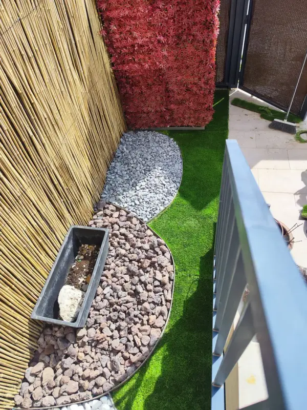 Otra vista de la terraza con piedra volcánica, grava y césped artificial