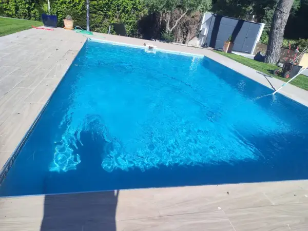 Piscina con agua limpia y borde de baldosa en un jardín privado